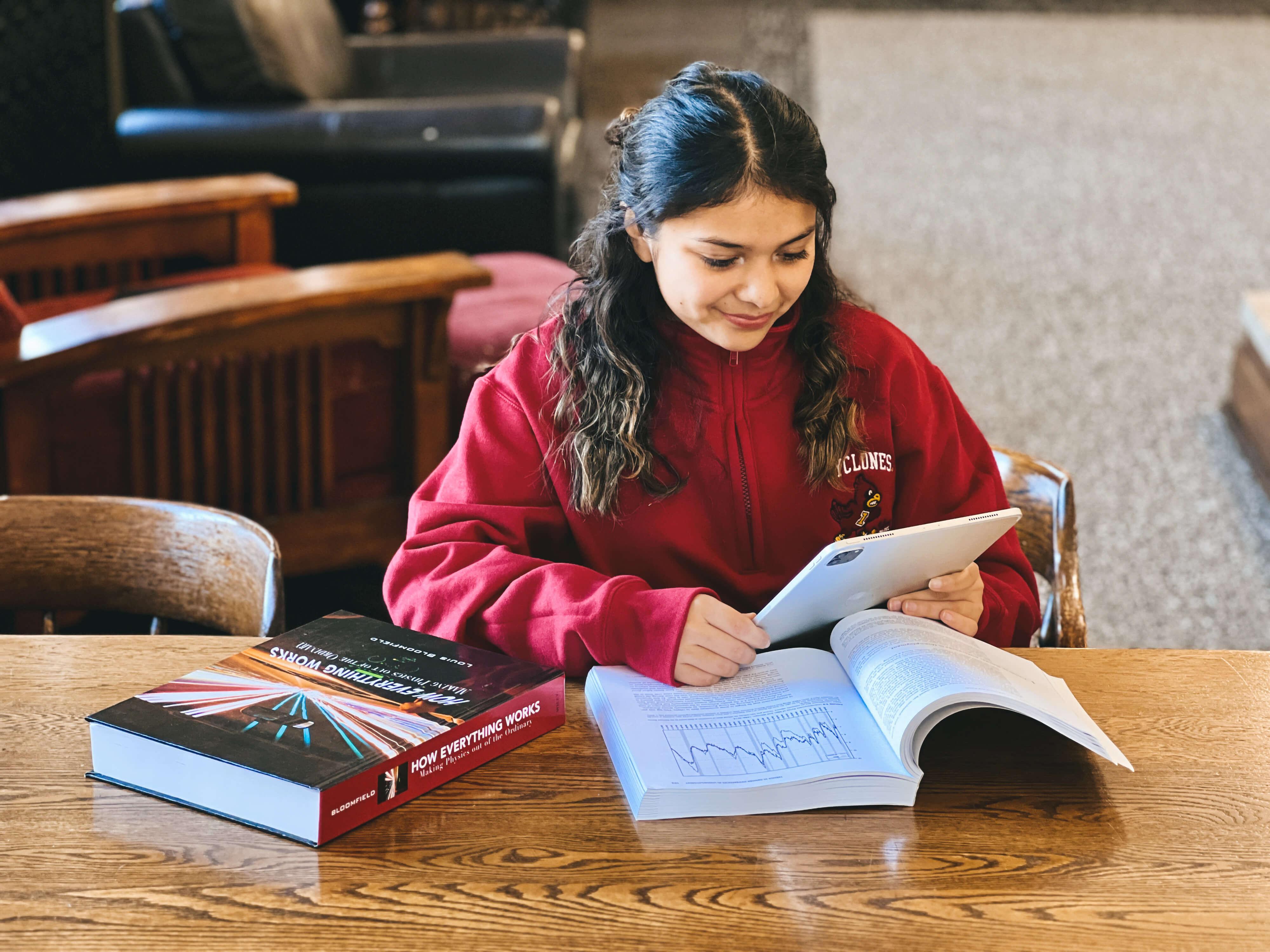 Student studying with an iPad and books